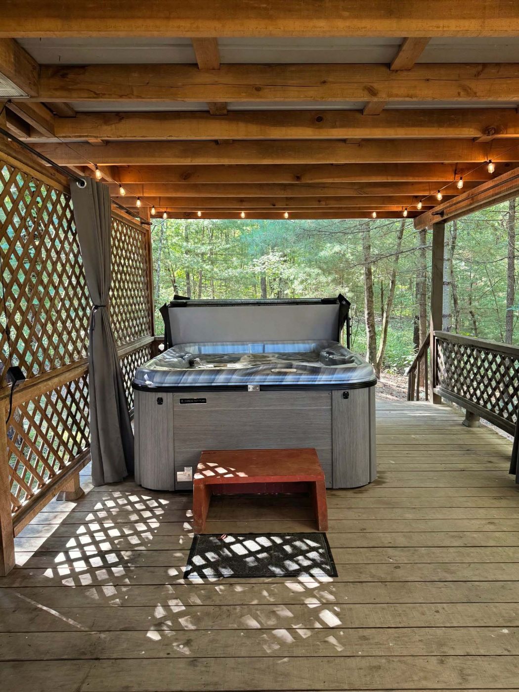 Private hot tub on the covered deck with string lights