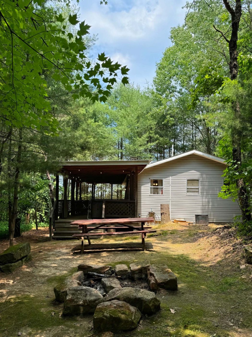 The Pinewood Cottage exterior with picnic table and stone campfire pit